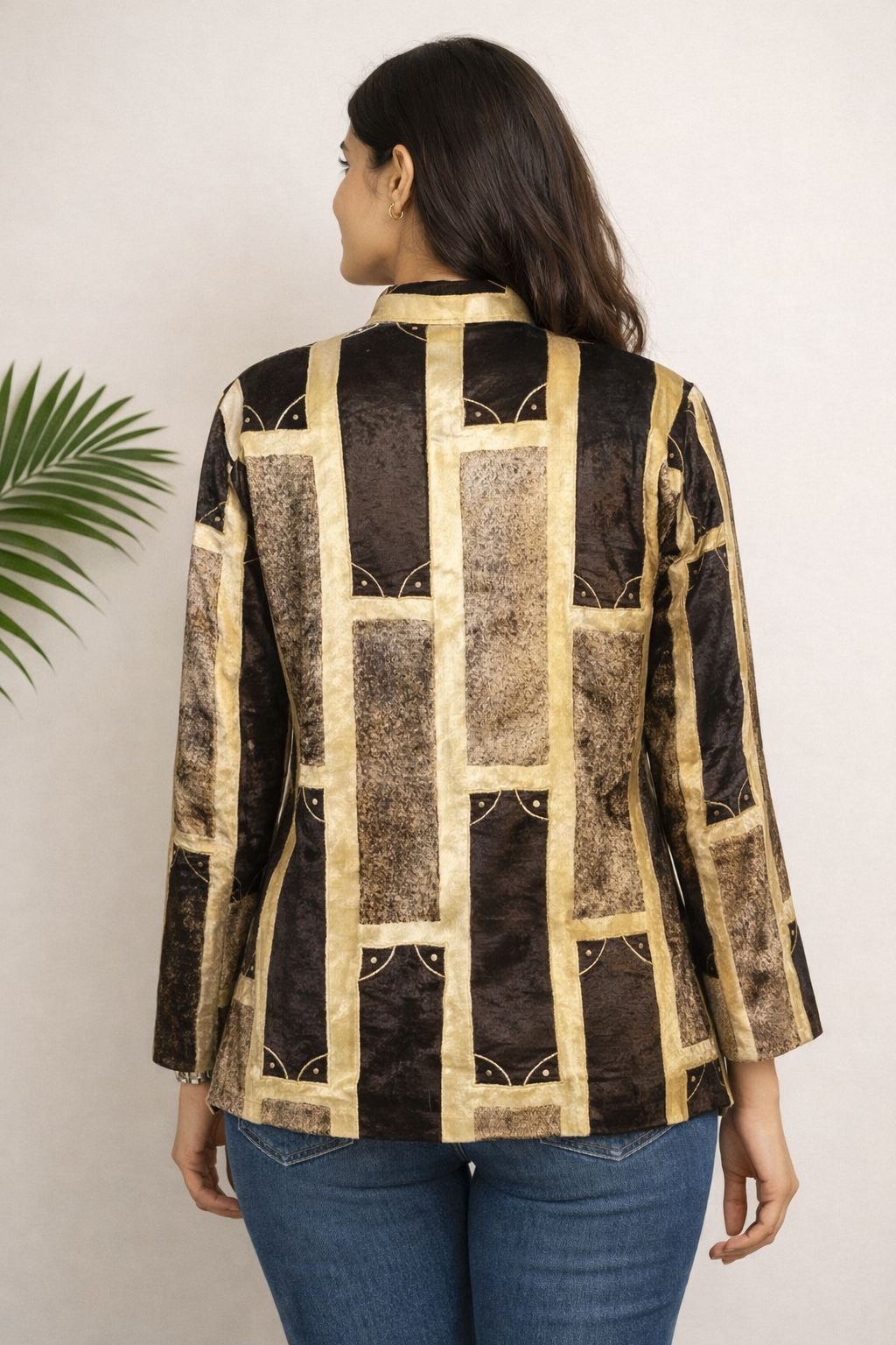 Woman wearing a black and gold patterned jacket against a white background