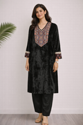 Woman wearing a black kurta with intricate embroidery on a white background